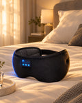 Black Bluetooth sleep mask with flat internal speakers, on a bed